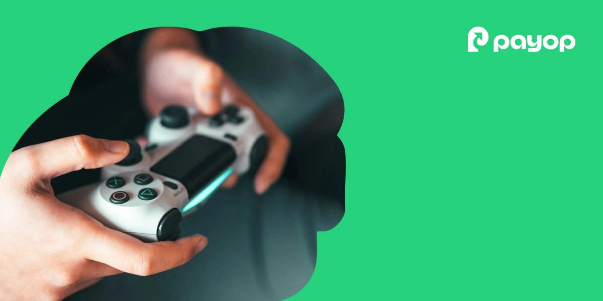 Hands holding a video game controller against a bright green background with the Payop logo. The scene conveys focus and engagement.