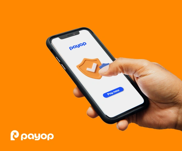 A hand holds a smartphone displaying a security icon and a "Pay now" button. The background is bright orange with the Payop logo.